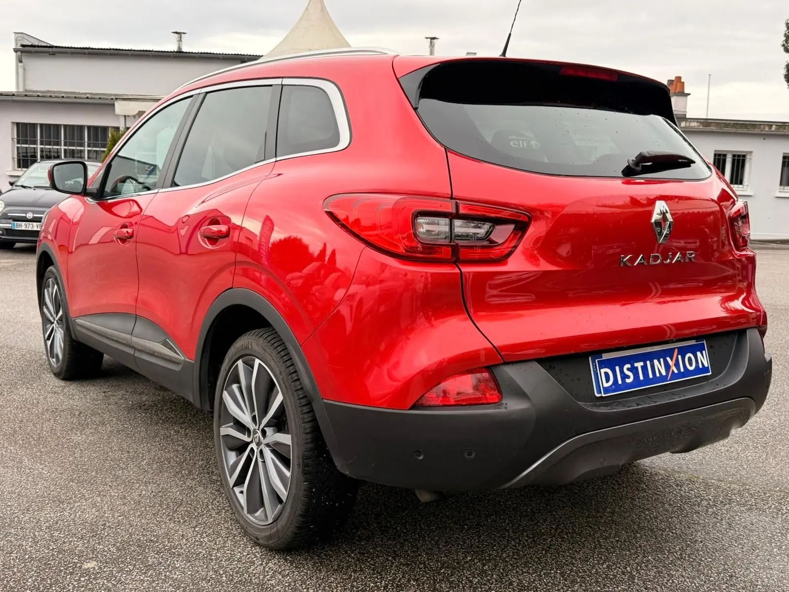 Renault Kadjar rouge flamme vu en 3/4 arrière droit, avec jantes alliage bi-ton et feux arrière LED distinctifs.