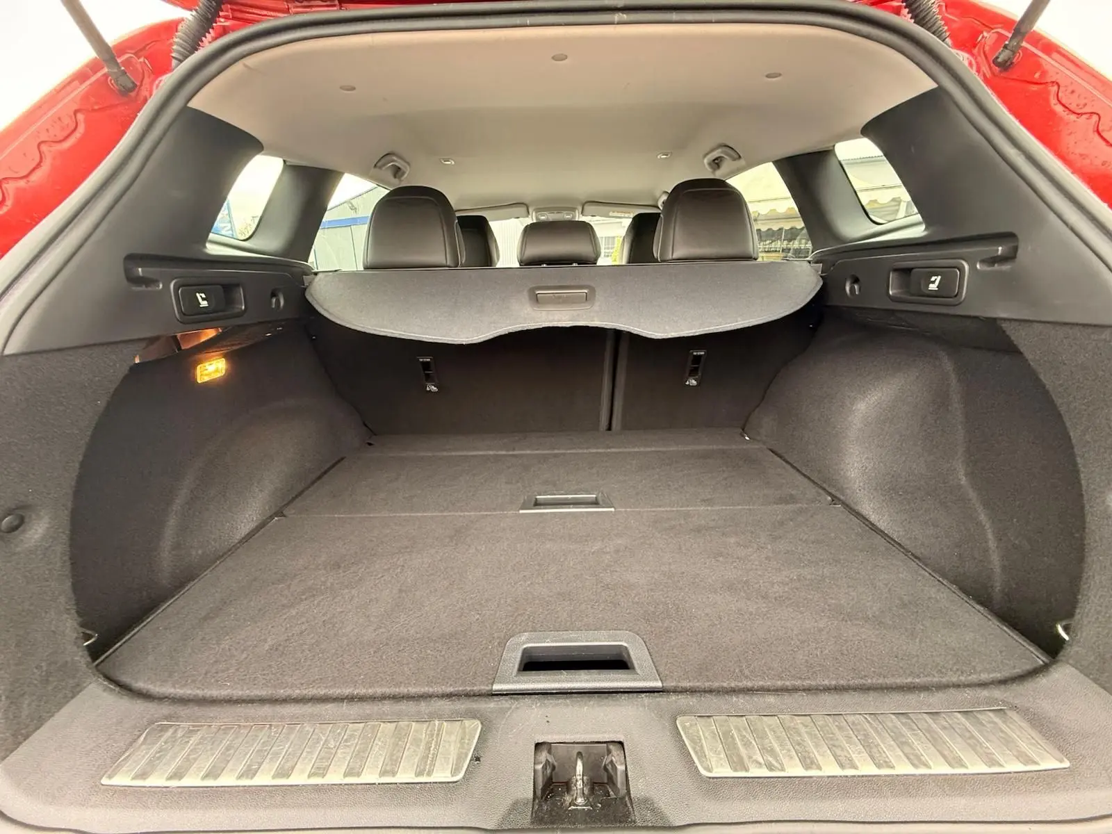 Vue intérieure du coffre ouvert du Renault Kadjar rouge flamme, montrant l'espace de chargement et la plage arrière.
