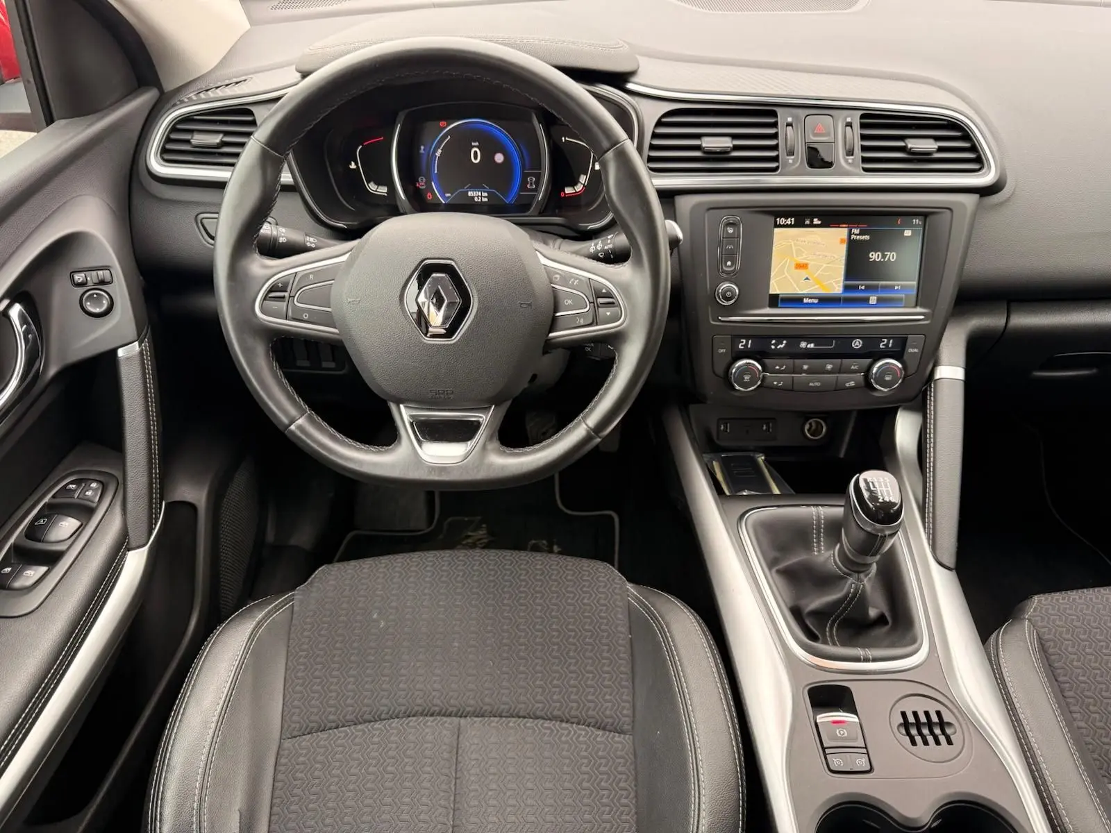 Vue intérieure centrée sur le volant et la console centrale du Renault Kadjar 1.2 TCE 130, sièges noirs et tableau de bord moderne.
