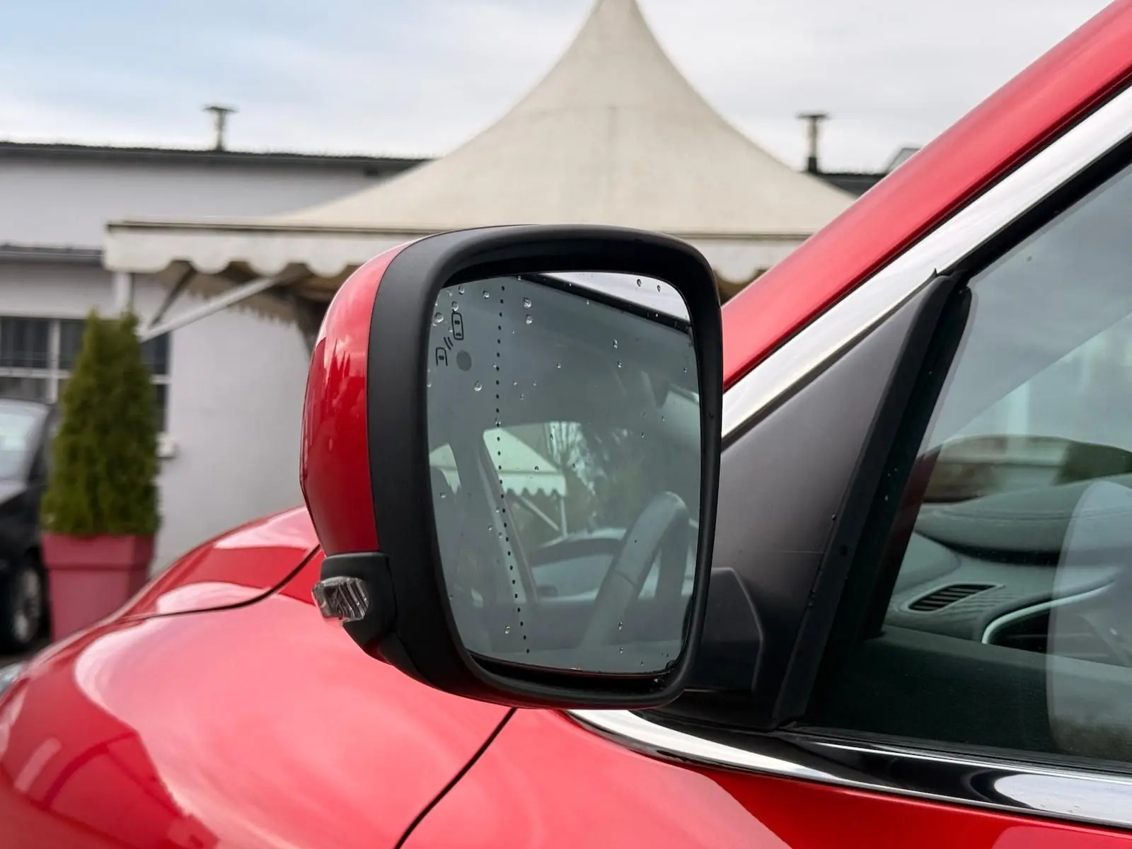 Rétroviseur côté gauche rouge flamme du Renault Kadjar 1.2 TCE 130 Energy INTENS avec gouttes d'eau visibles.