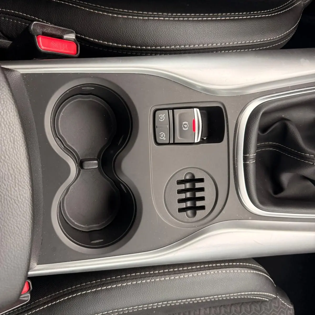 Vue plongeante sur la console centrale noire du Renault Kadjar 2016 avec porte-gobelets et frein à main électrique.