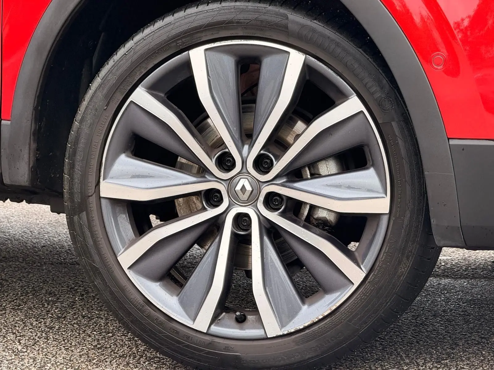 Gros plan sur la roue avant gauche du Renault Kadjar rouge flamme, mettant en valeur la jante alliage bi-ton au design moderne.