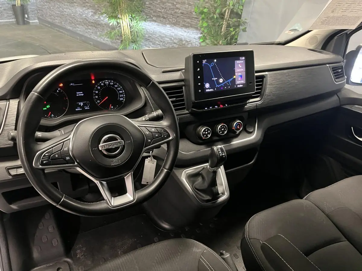 Vue intérieure côté conducteur du tableau de bord noir du Nissan Primastar avec écran tactile et volant multifonctions.