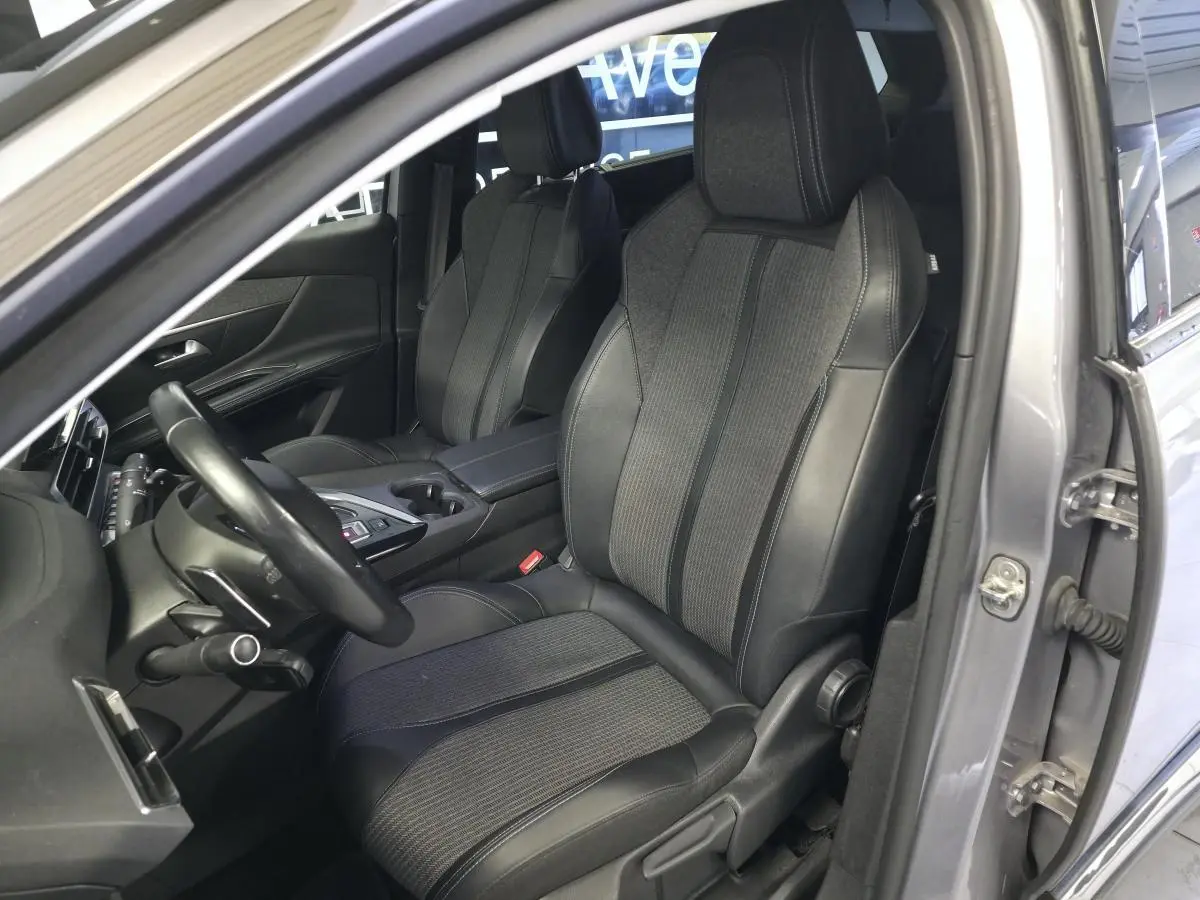 Vue intérieure côté conducteur du Peugeot 5008 gris 2022, sièges TEP et tissu Colyn avec volant cuir et console centrale.