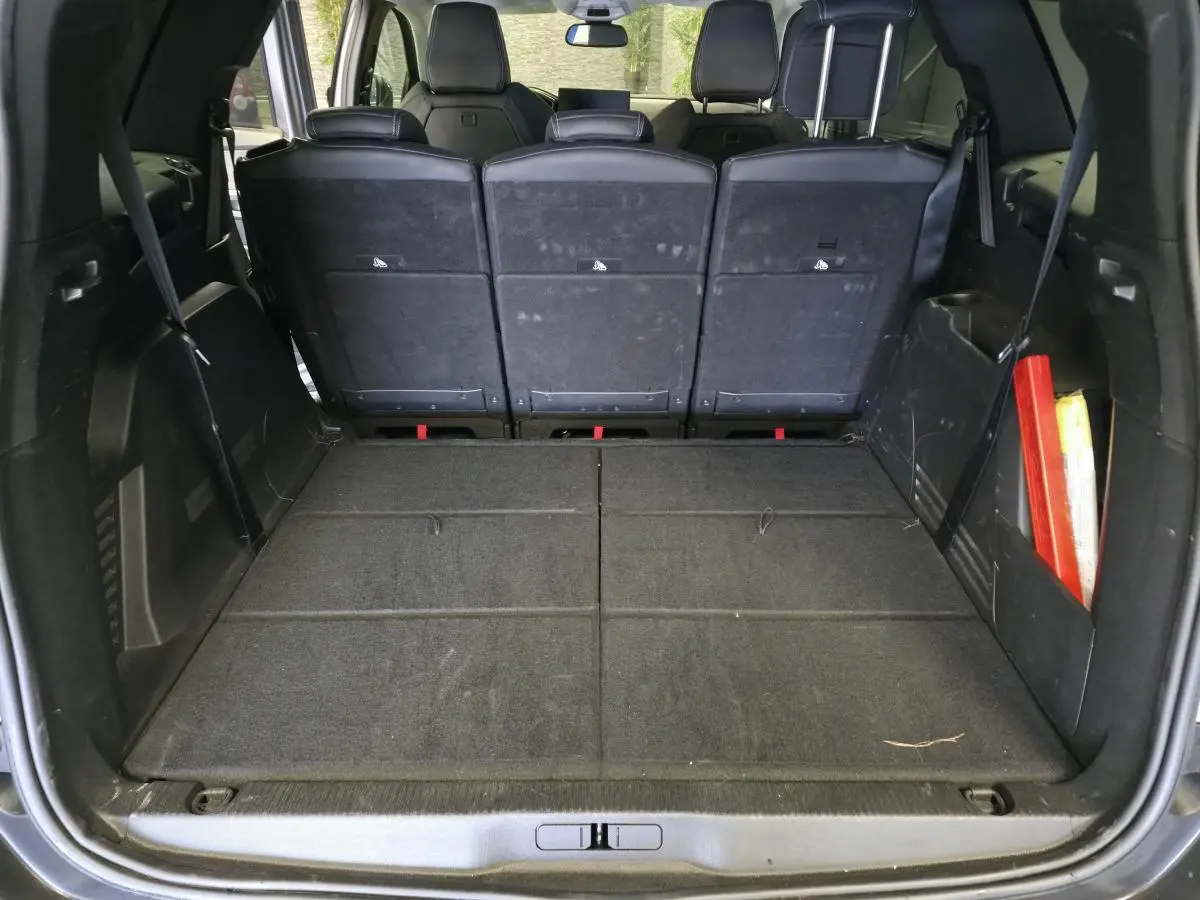 Coffre ouvert vu de l'arrière d'un Peugeot 5008 gris, montrant les sièges arrière relevés et un espace de chargement plat.