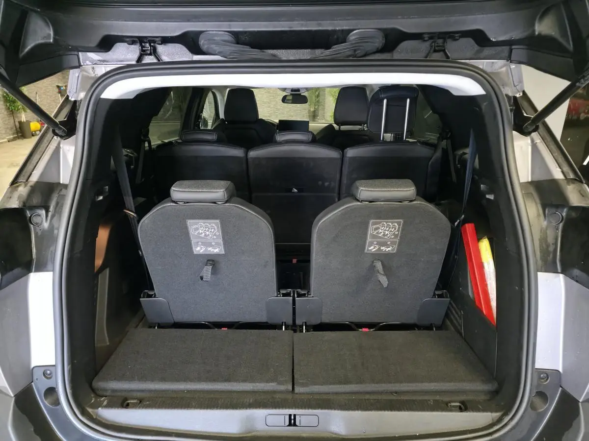 Coffre ouvert d'un Peugeot 5008 gris 2022, montrant les sièges escamotés du troisième rang et l'intérieur noir.