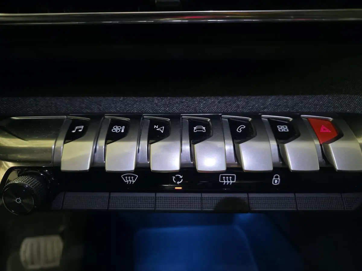 Gros plan sur les commandes argentées du tableau de bord du Peugeot 5008 2022, éclairage bleu en dessous.