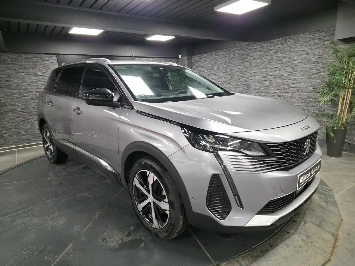 Peugeot 5008 gris métallisé vue 3/4 avant droit, avec calandre à damier chromé et jantes alliage bi-ton.