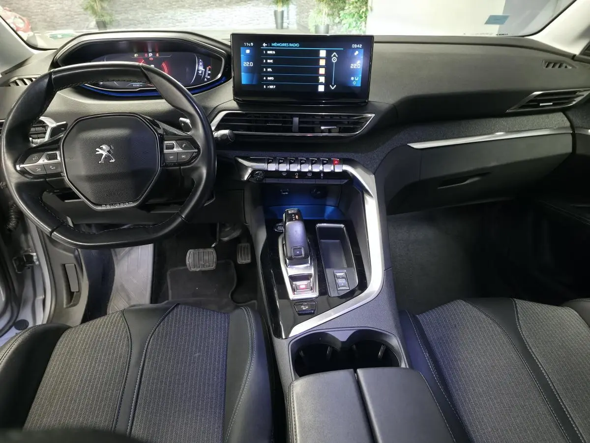 Intérieur noir du Peugeot 5008 2022, vue du poste de conduite avec volant compact et écran tactile central lumineux.