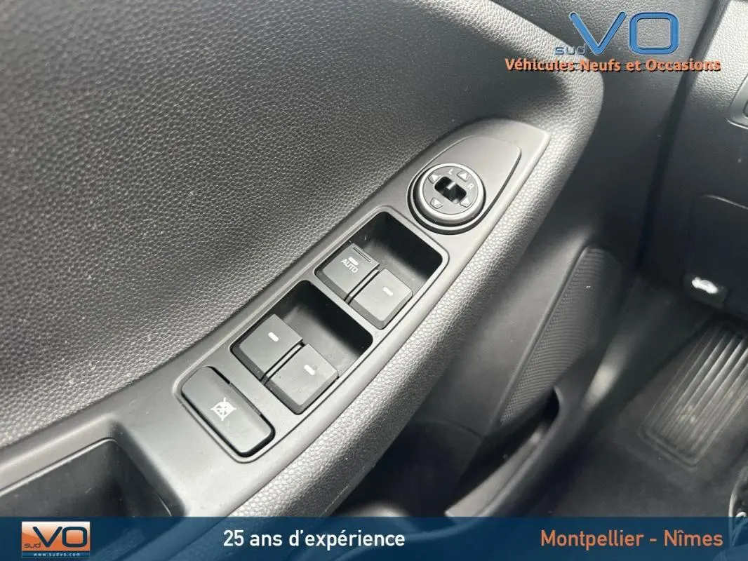 Gros plan sur les commandes des vitres électriques côté conducteur d'une Hyundai i20 blanche, version 2019.