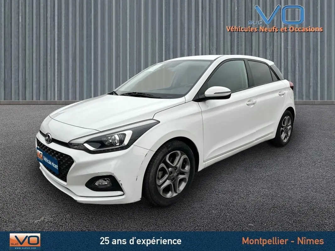Vue 3/4 avant droite d'une Hyundai i20 blanche 2019 avec jantes alliage et phares LED distinctifs.