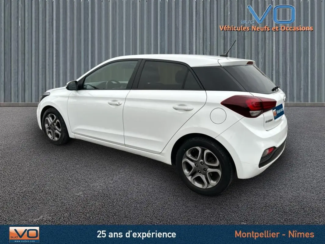 Vue côté gauche arrière d'une Hyundai i20 blanche 2019 avec vitres teintées et jantes alliage.