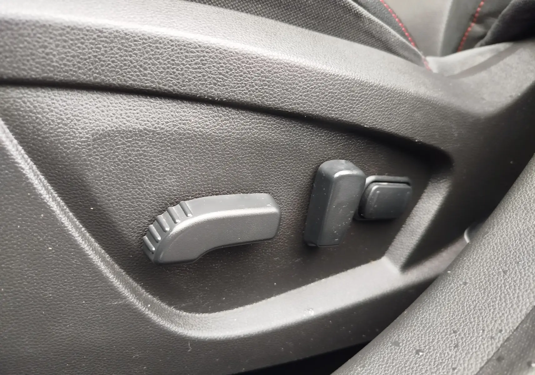 Gros plan sur les commandes de réglage électrique du siège avant en cuir noir du Renault Arkana bleu Zanzibar.