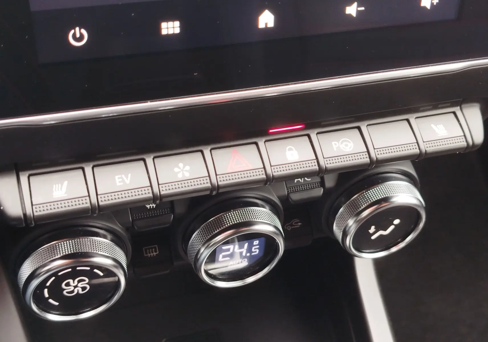 Gros plan sur la console centrale du Renault Arkana bleu Zanzibar 2022, montrant les commandes de climatisation et les boutons fonctionnels.