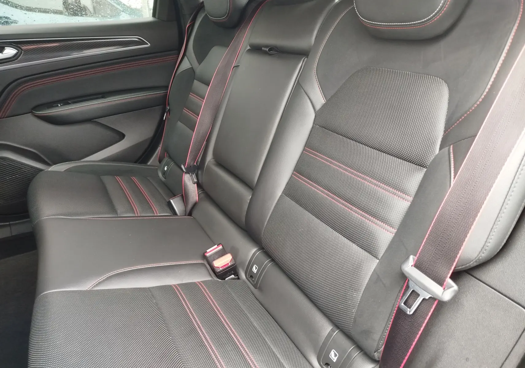 Vue intérieure côté droit des sièges arrière noirs avec surpiqûres rouges du Renault Arkana 1.6 E-Tech 145ch RS Line 2022.