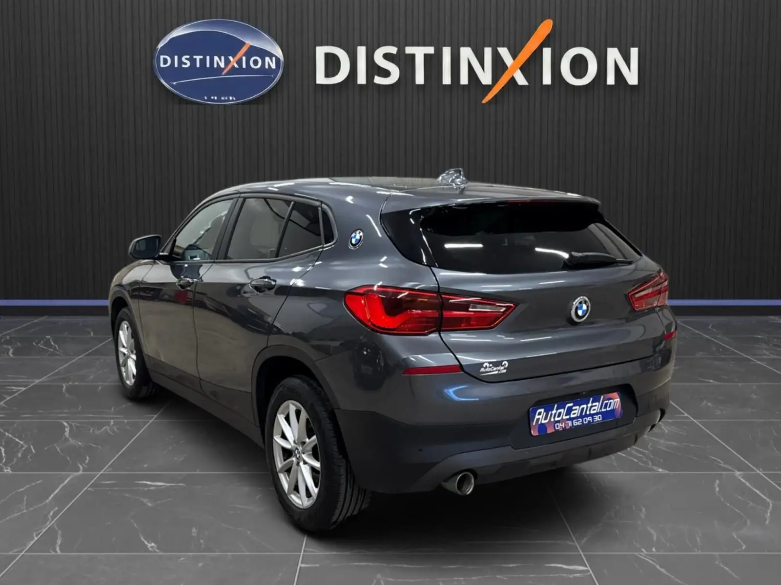 Vue 3/4 arrière droite d'un BMW X2 gris minéral métallisé avec vitres arrière surteintées dans un showroom.