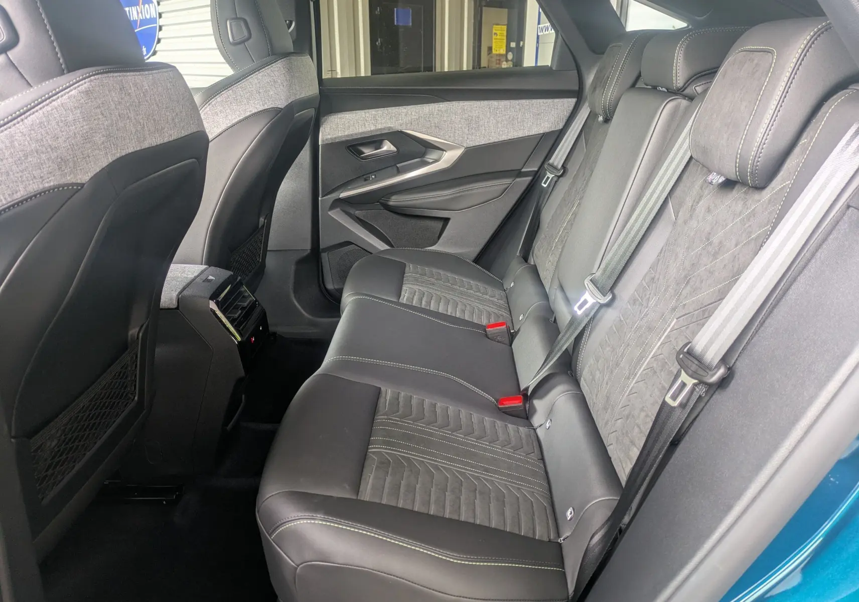 Vue latérale droite de l'intérieur arrière du Peugeot 3008 Hybrid 2026, sièges en Alcantara noir avec surpiqûres claires.