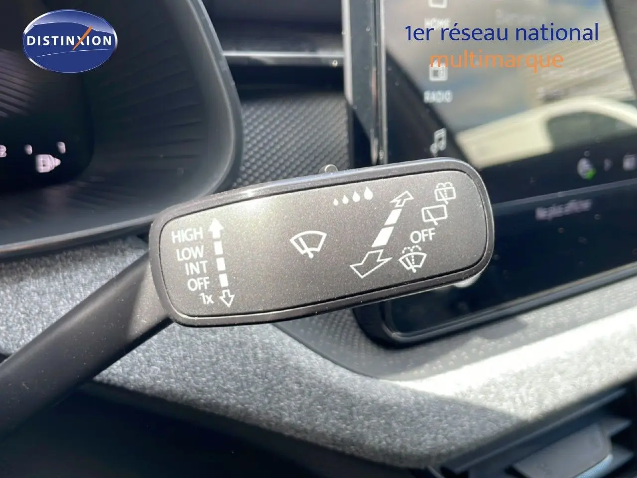 Gros plan sur la manette d’essuie-glace à gauche du volant dans l’habitacle gris noir d’une Skoda Scala blanc glacier.