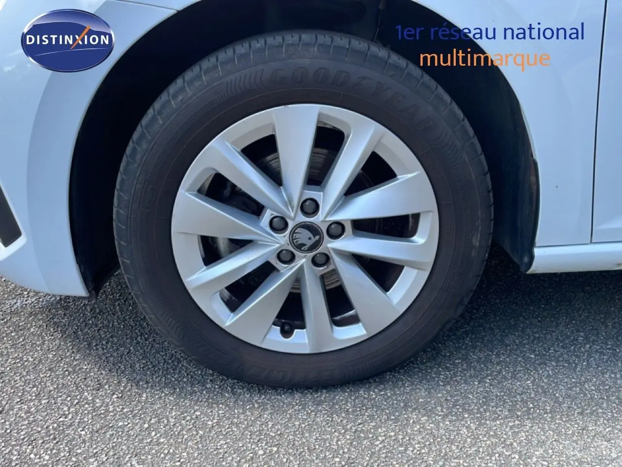 Gros plan sur la roue avant gauche d'une Skoda Scala blanc glacier avec jante alliage à 10 branches.