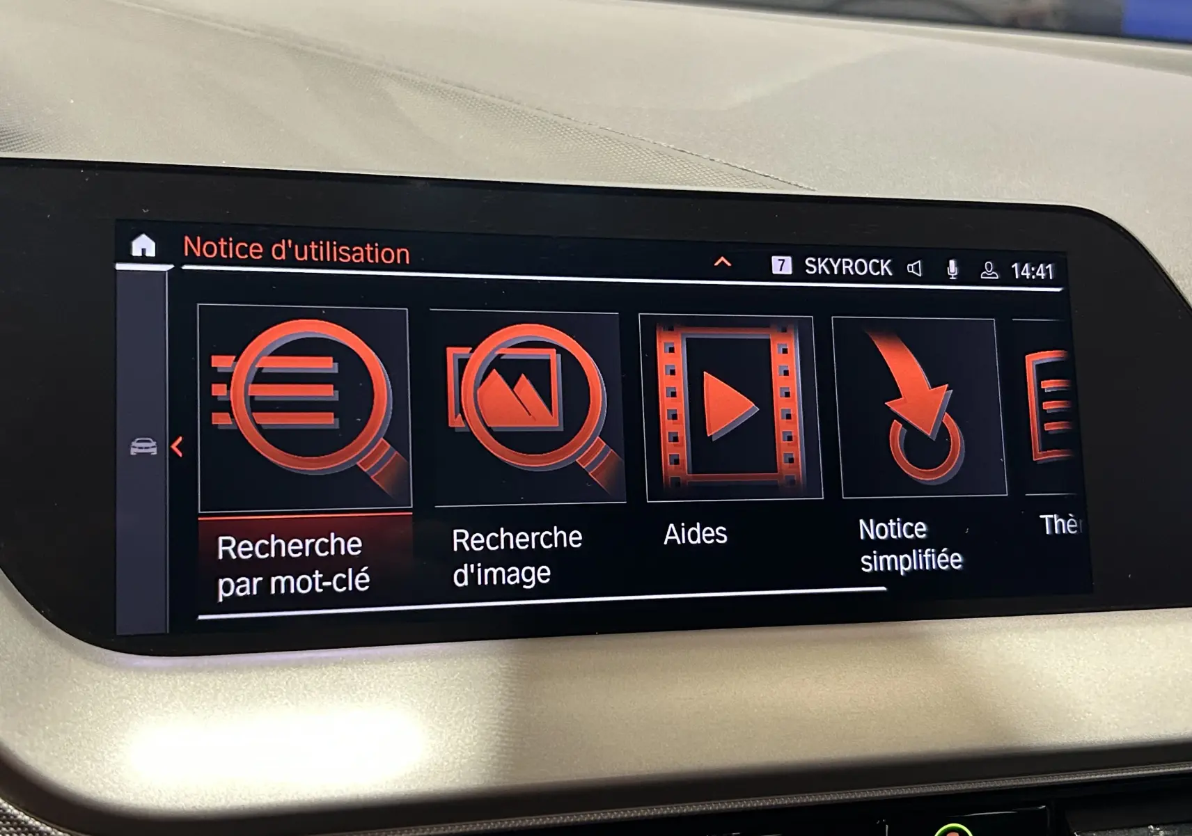 Écran tactile intérieur du système GPS de la BMW Série 1 16d 2023, affichant le menu d'aide en rouge et noir.