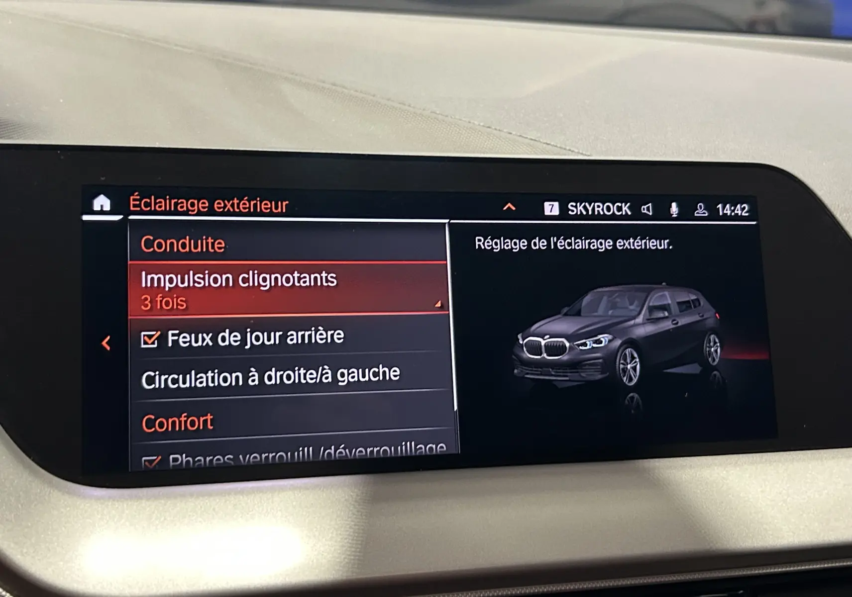 Écran central montrant le menu de réglage de l'éclairage extérieur avec une illustration 3/4 avant d'une BMW Série 1 noire.