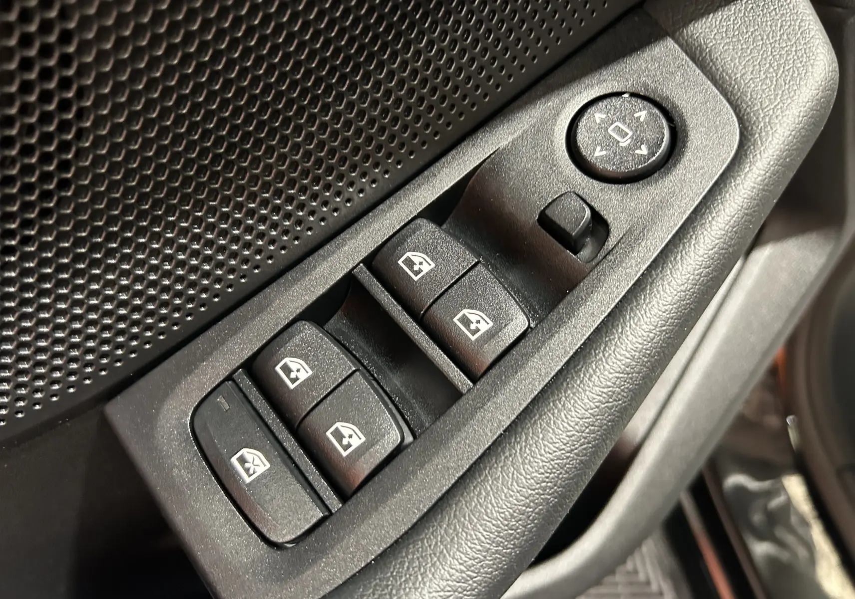 Gros plan sur les commandes de lève-vitres et réglage des rétroviseurs côté conducteur d’une BMW Série 1 noire 2023.