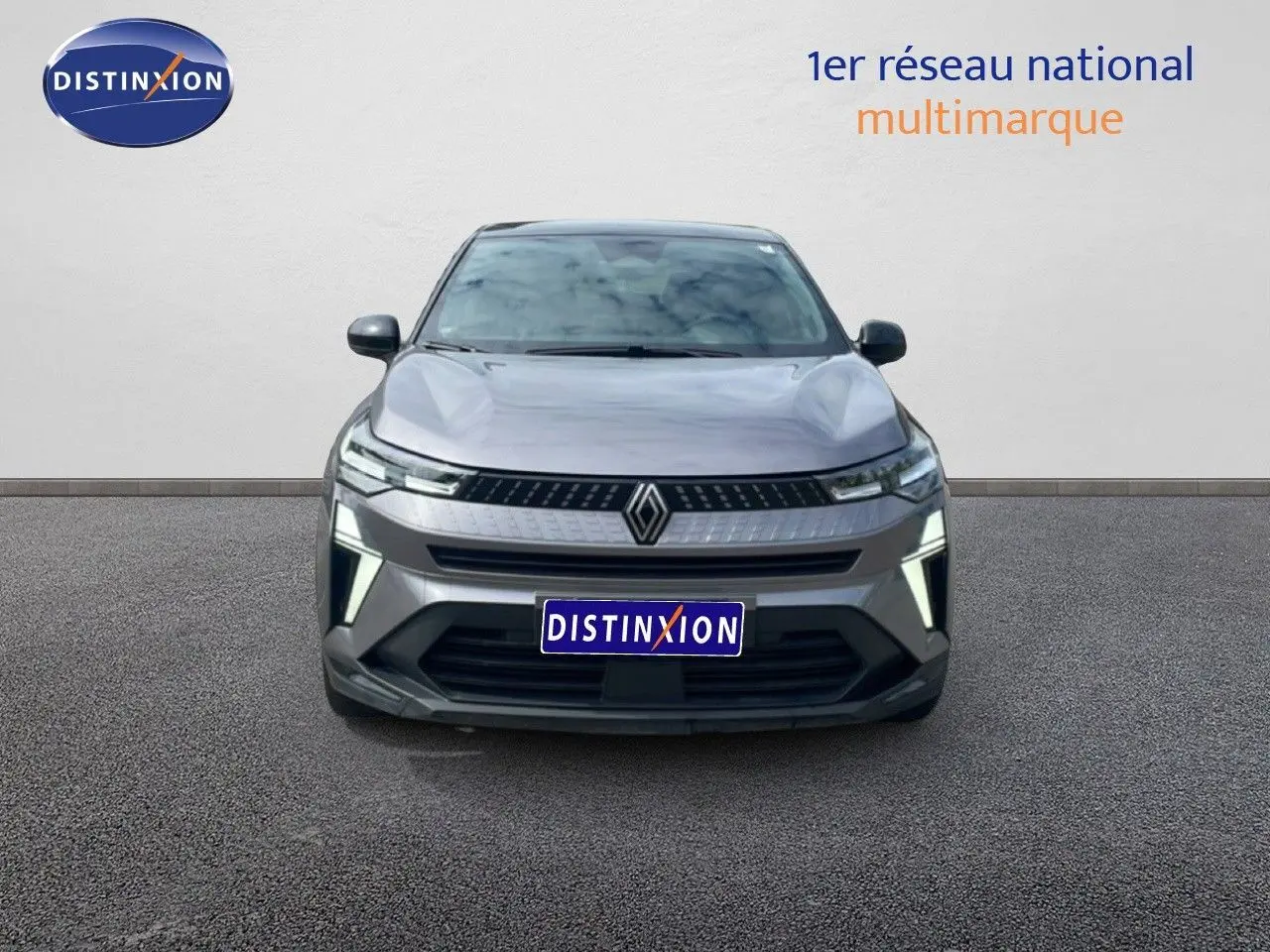 Vue frontale du Renault Captur 2025 gris Cassiopée métal avec toit noir et feux LED allumés sur fond neutre.