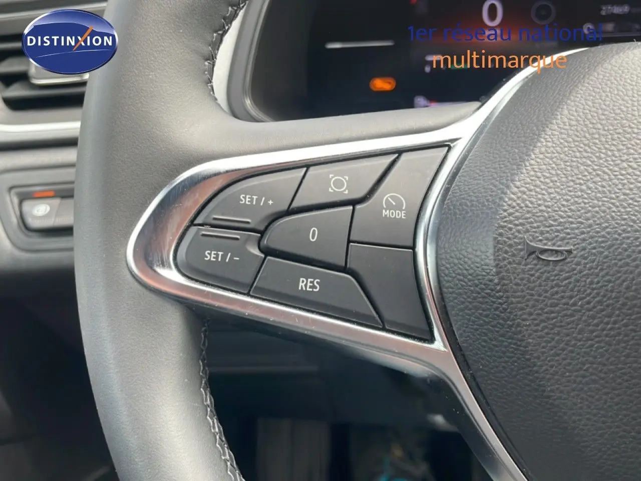 Gros plan sur les commandes gauche du volant en cuir noir du Renault Captur 2025, avec boutons de régulateur de vitesse.