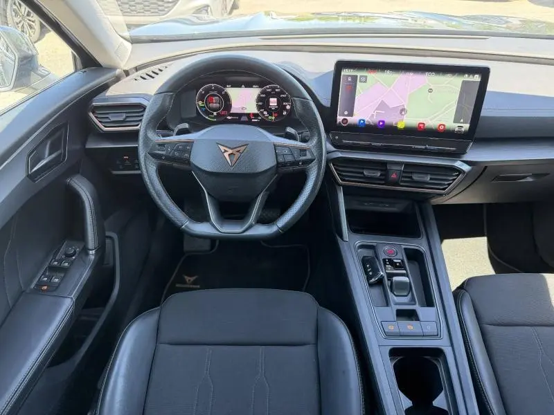 Vue intérieure frontale du tableau de bord du CUPRA Formentor 1.4 e-HYBRID 2024 avec écran tactile et volant sport noir.