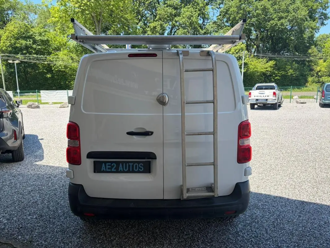 Vue arrière d’un Peugeot Expert Fourgon blanc avec galerie et échelle métallique fixée sur la porte droite.