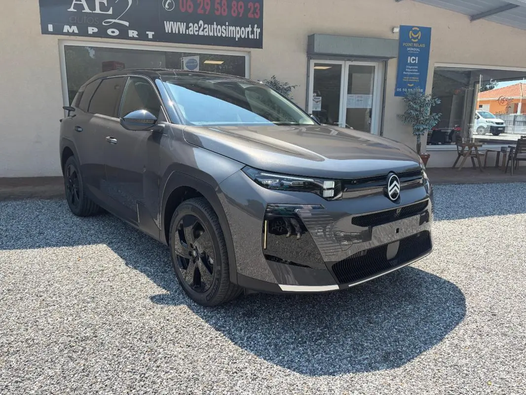 Citroën C5 Aircross gris en 3/4 avant droit, avec jantes noires et calandre moderne, stationné devant un bâtiment.