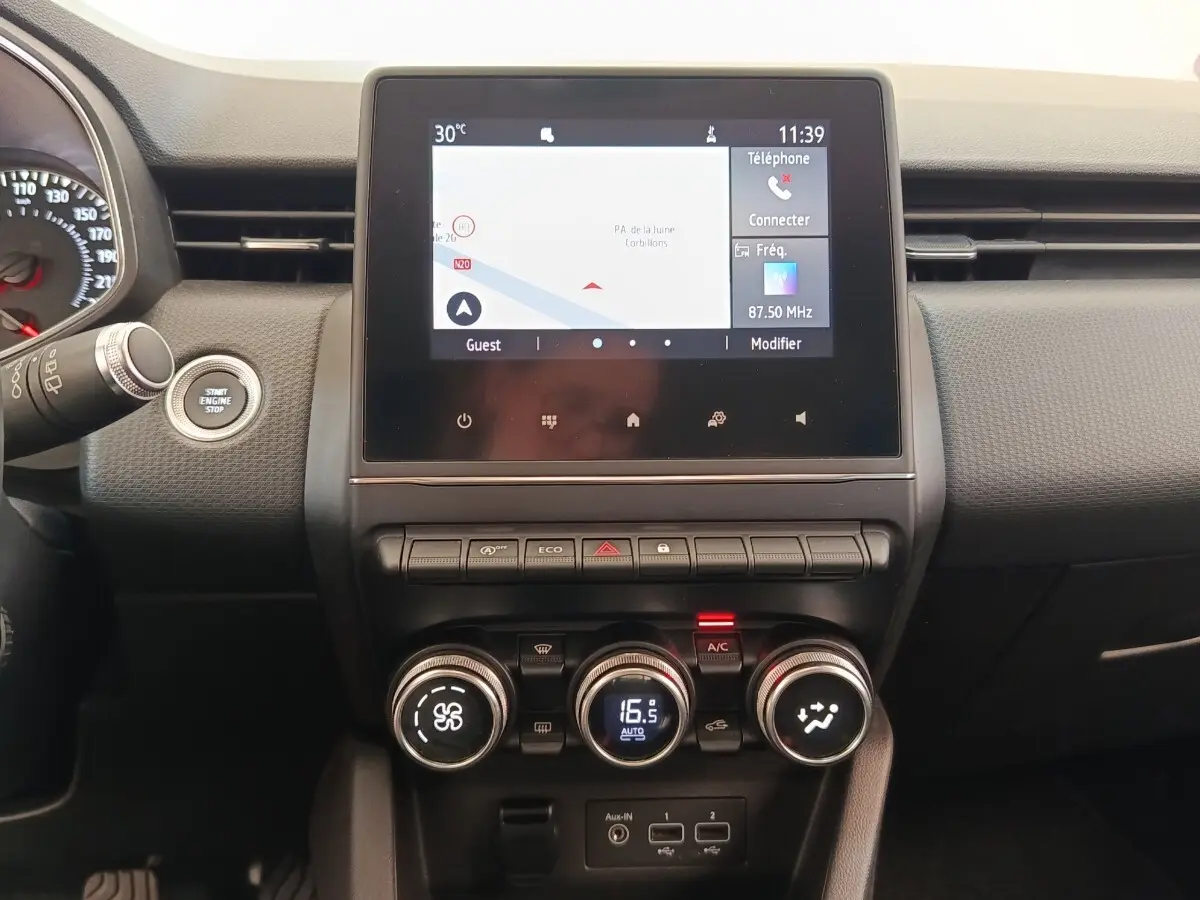 Vue rapprochée du tableau de bord de la Renault Clio Business TCe 100, écran tactile avec navigation et commandes de climatisation.