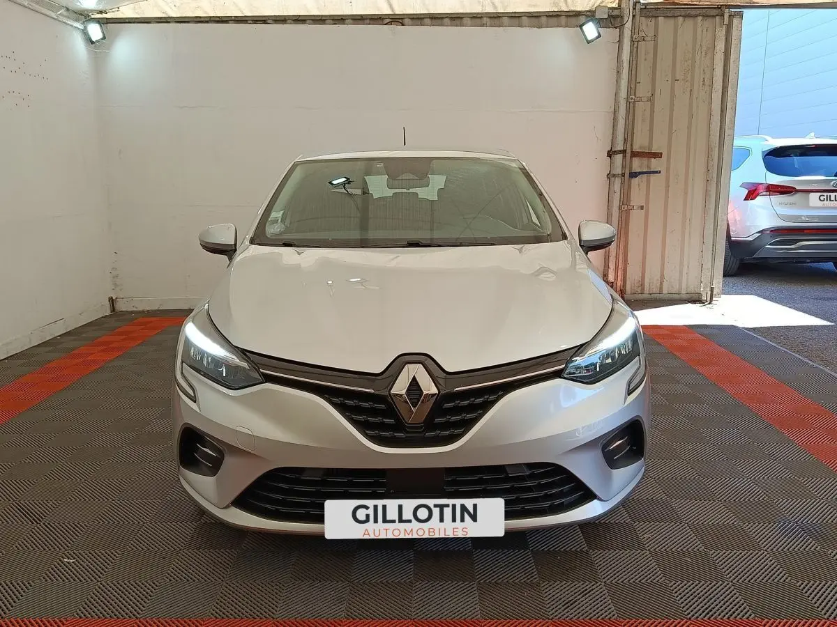 Vue avant d'une Renault Clio Business TCe 100 gris clair avec feux LED allumés dans un garage.