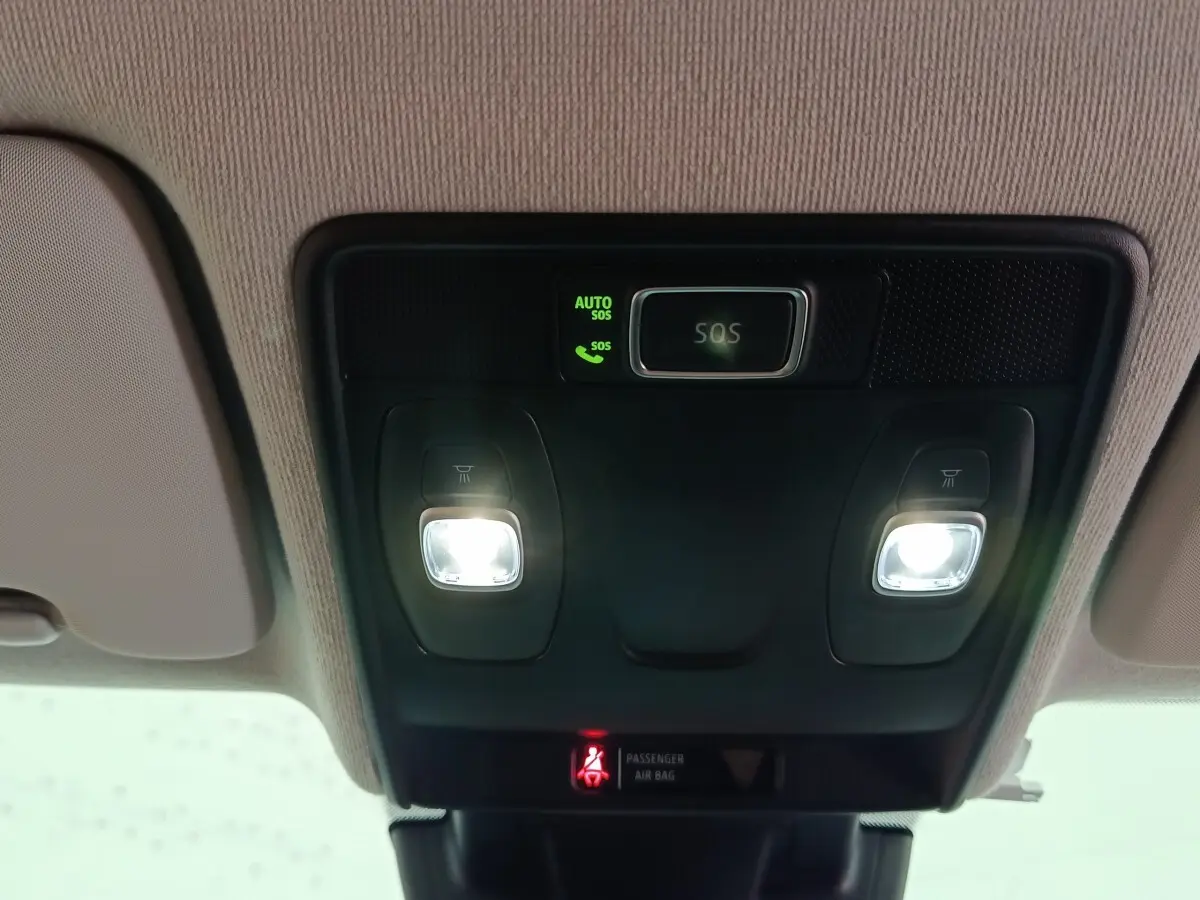 Vue intérieure en gros plan du plafonnier avec éclairages de lecture et bouton SOS allumé dans une Renault Clio gris clair.