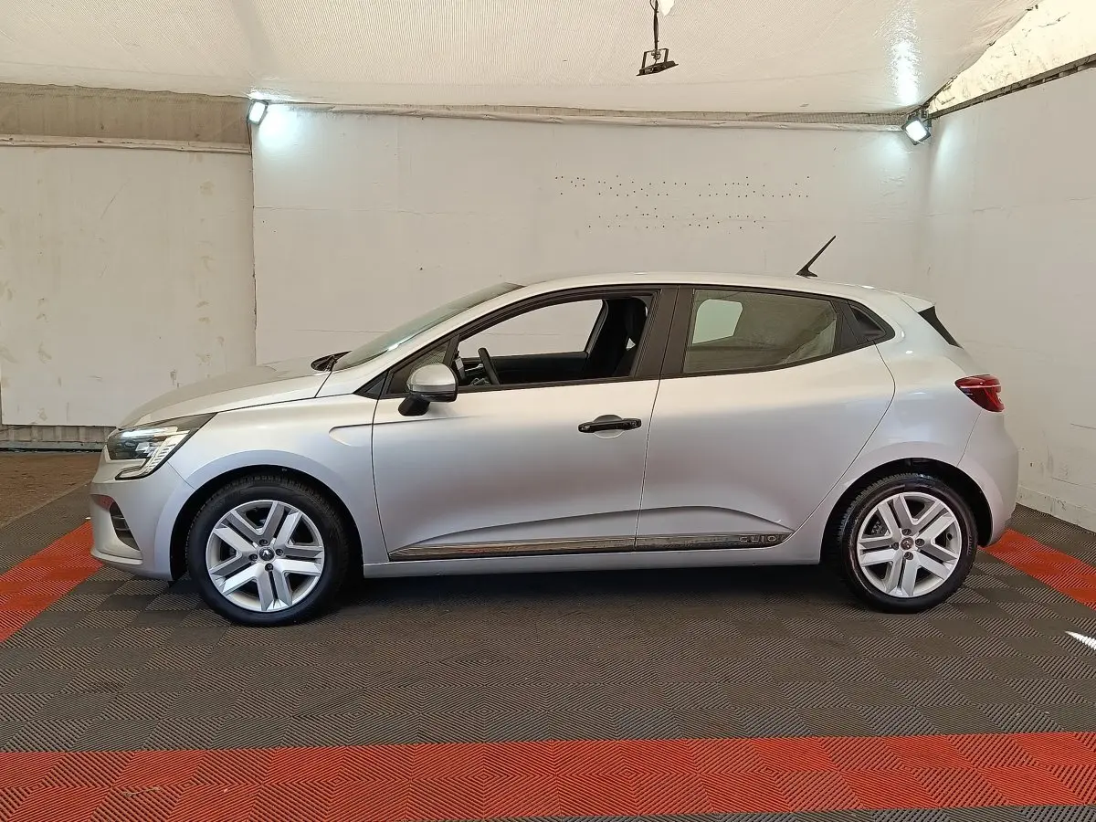 Renault Clio Business TCe 100 gris clair vue de profil côté gauche dans un espace intérieur éclairé.
