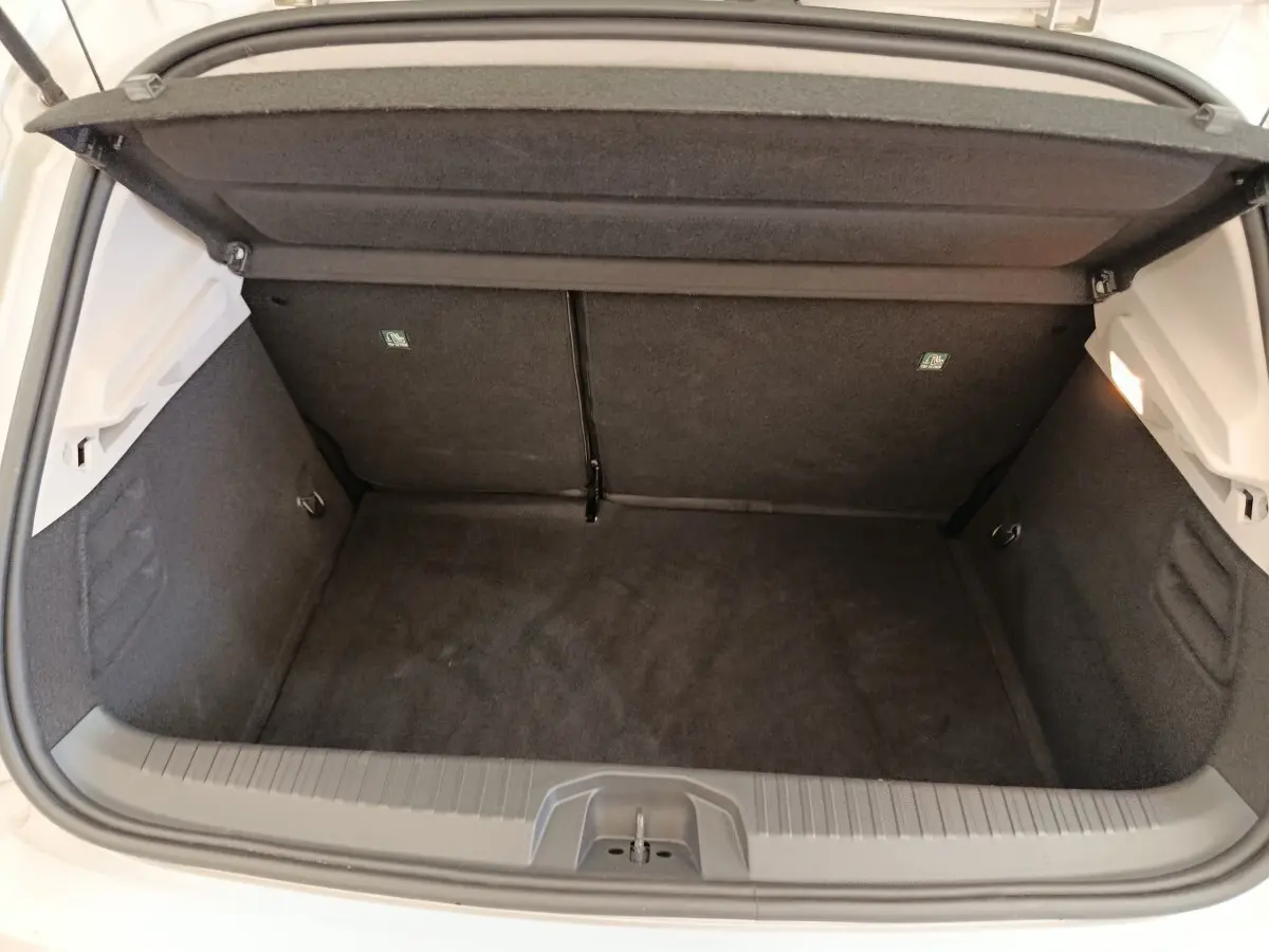 Coffre ouvert vu de l'arrière d'une Renault Clio gris clair, montrant un espace de rangement propre et vide.