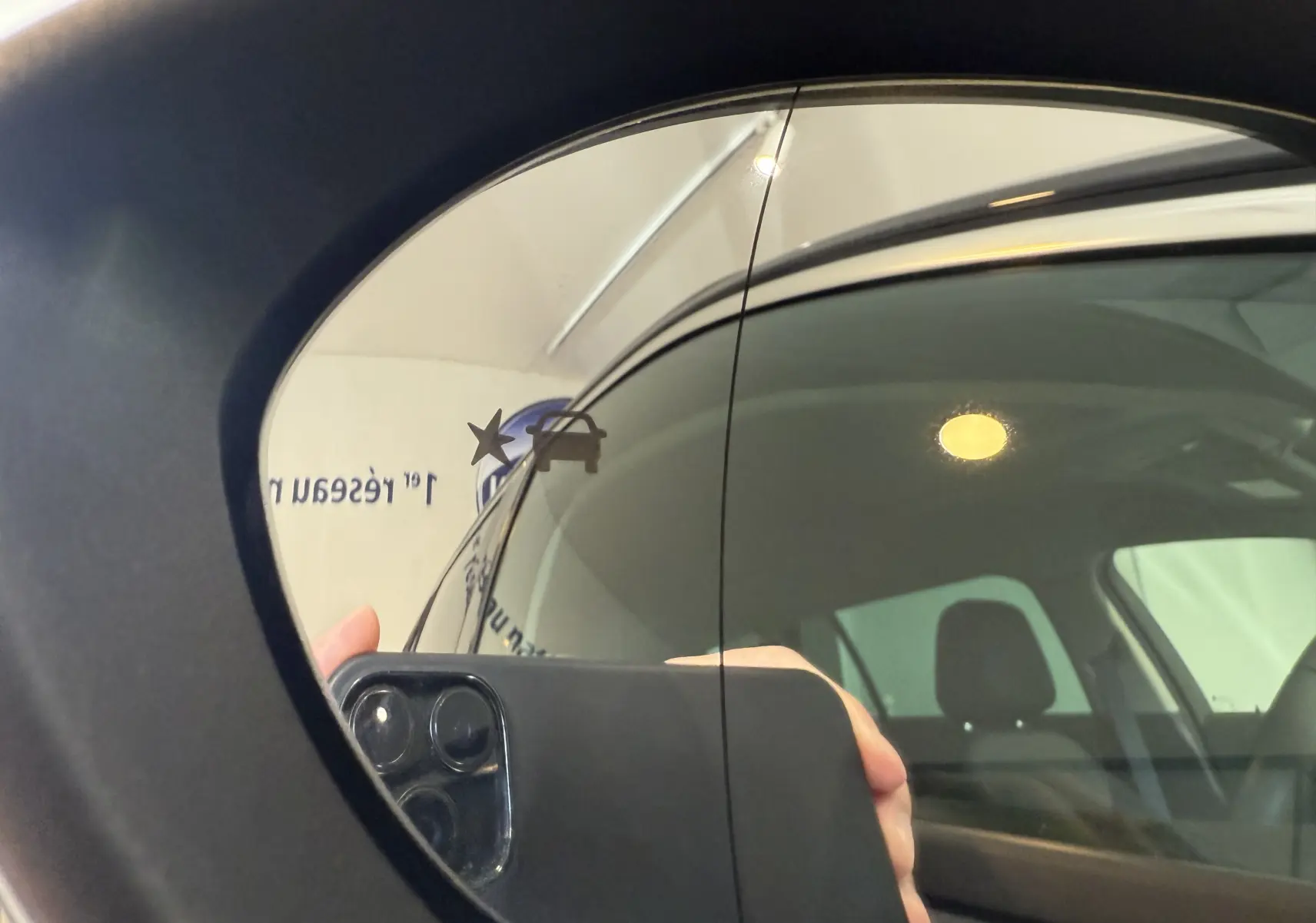 Reflet dans le rétroviseur latéral gauche d'une Opel Insignia Sports Tourer bleu lune marine métal, montrant la vitre et l'intérieur.
