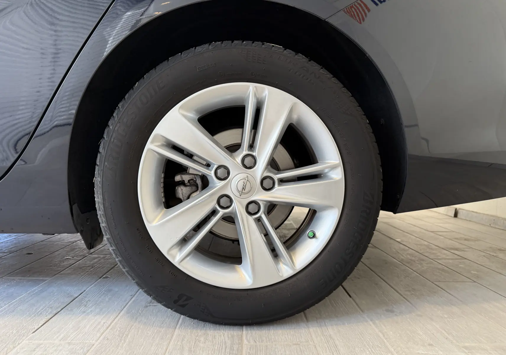 Gros plan sur la roue avant gauche de l'Opel Insignia Sports Tourer bleu lune marine métal avec jante argentée cinq branches.