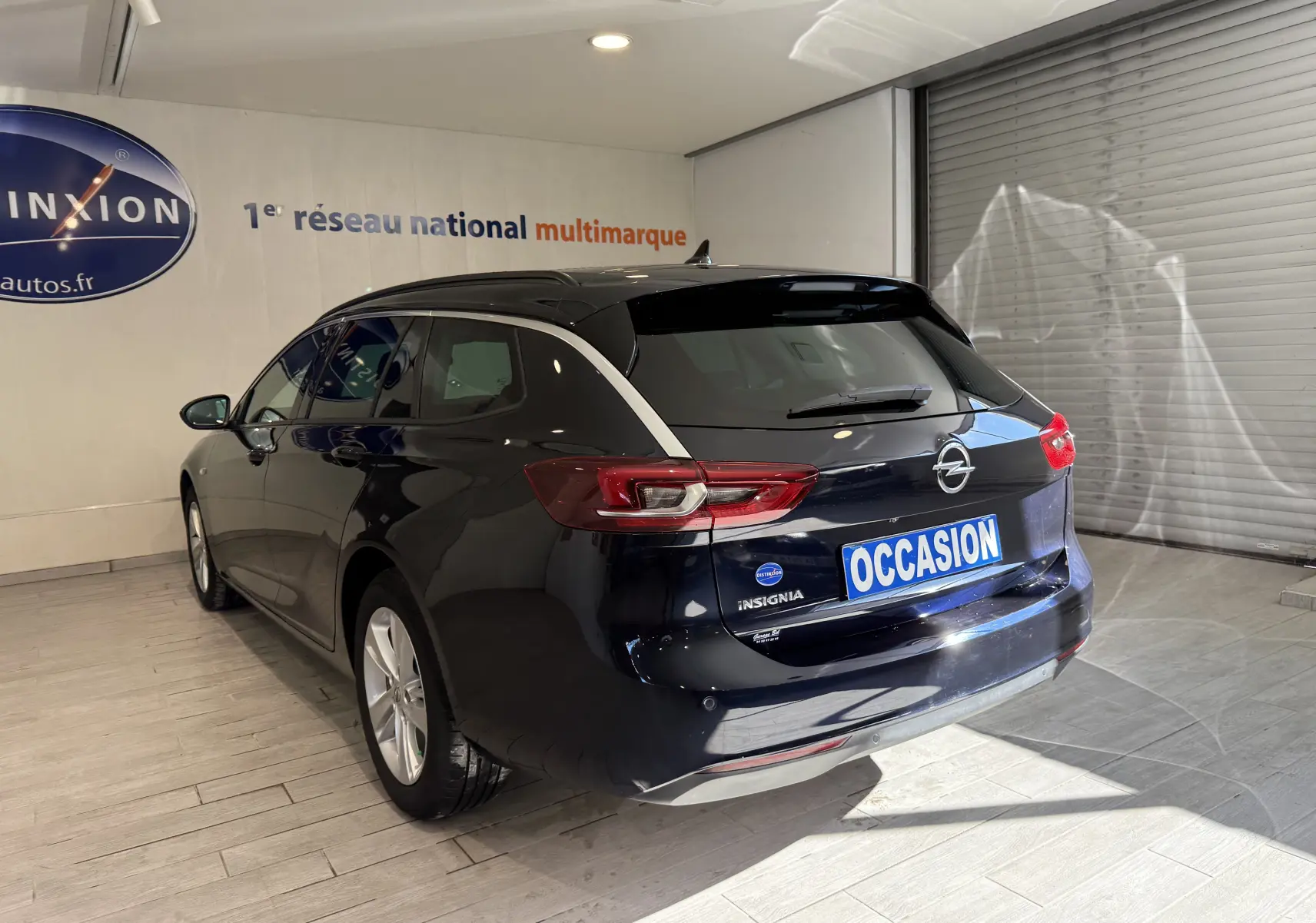 Opel Insignia Sports Tourer bleu lune marine métal vue 3/4 arrière droit en intérieur avec plaque occasion.