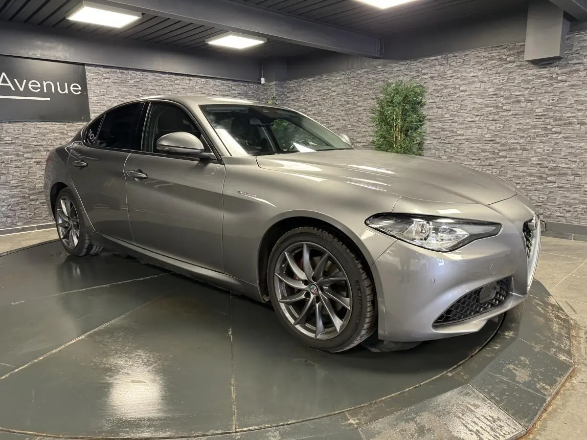 Alfa Romeo Giulia gris métallisé vue 3/4 avant droit avec jantes alliage 18 pouces Aero Scuro et vitres arrière surteintées.