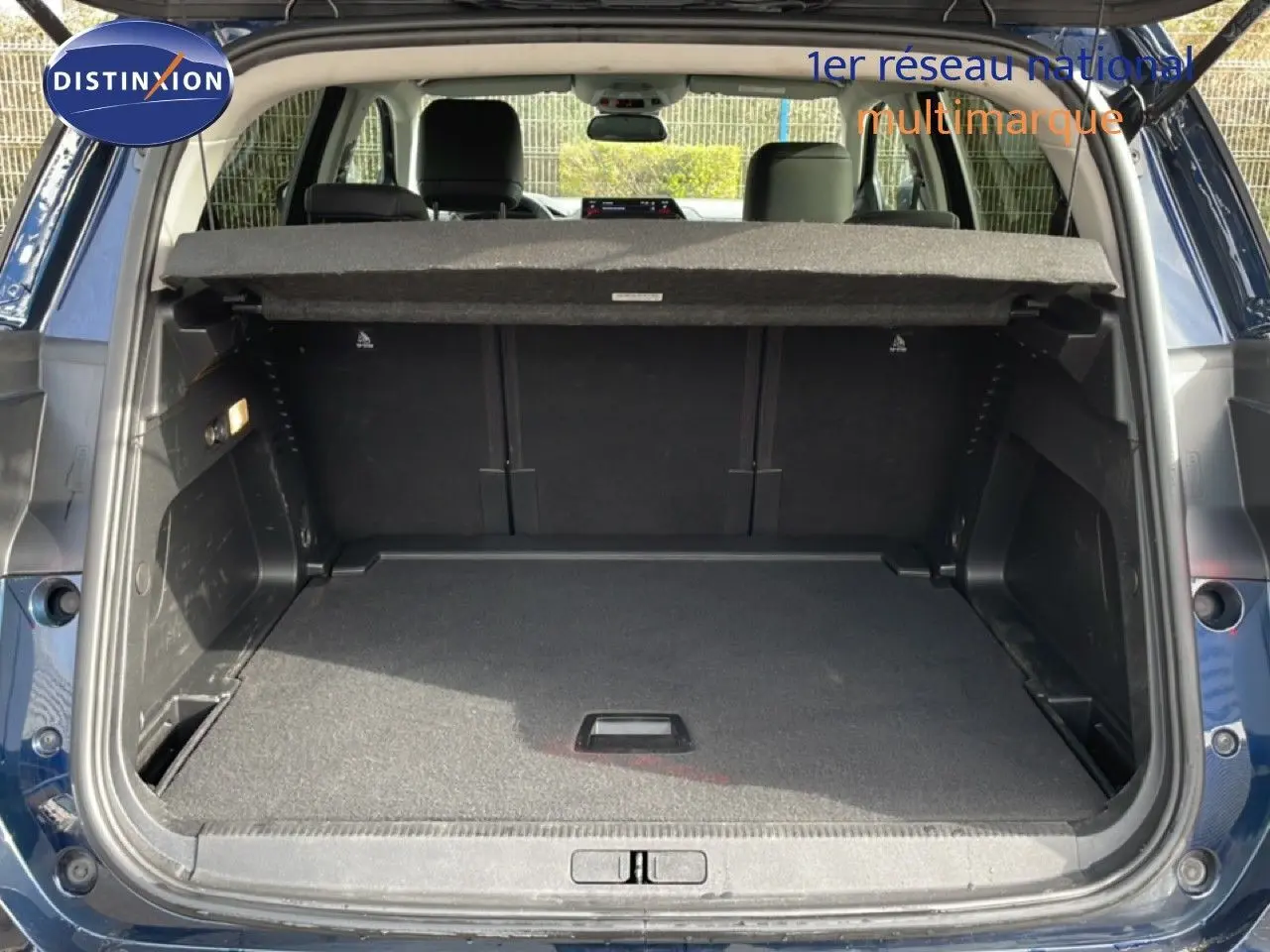 Coffre ouvert d’un Citroën C5 Aircross bleu Eclipse Metal, vue arrière montrant l’espace de chargement vide et la tablette arrière.