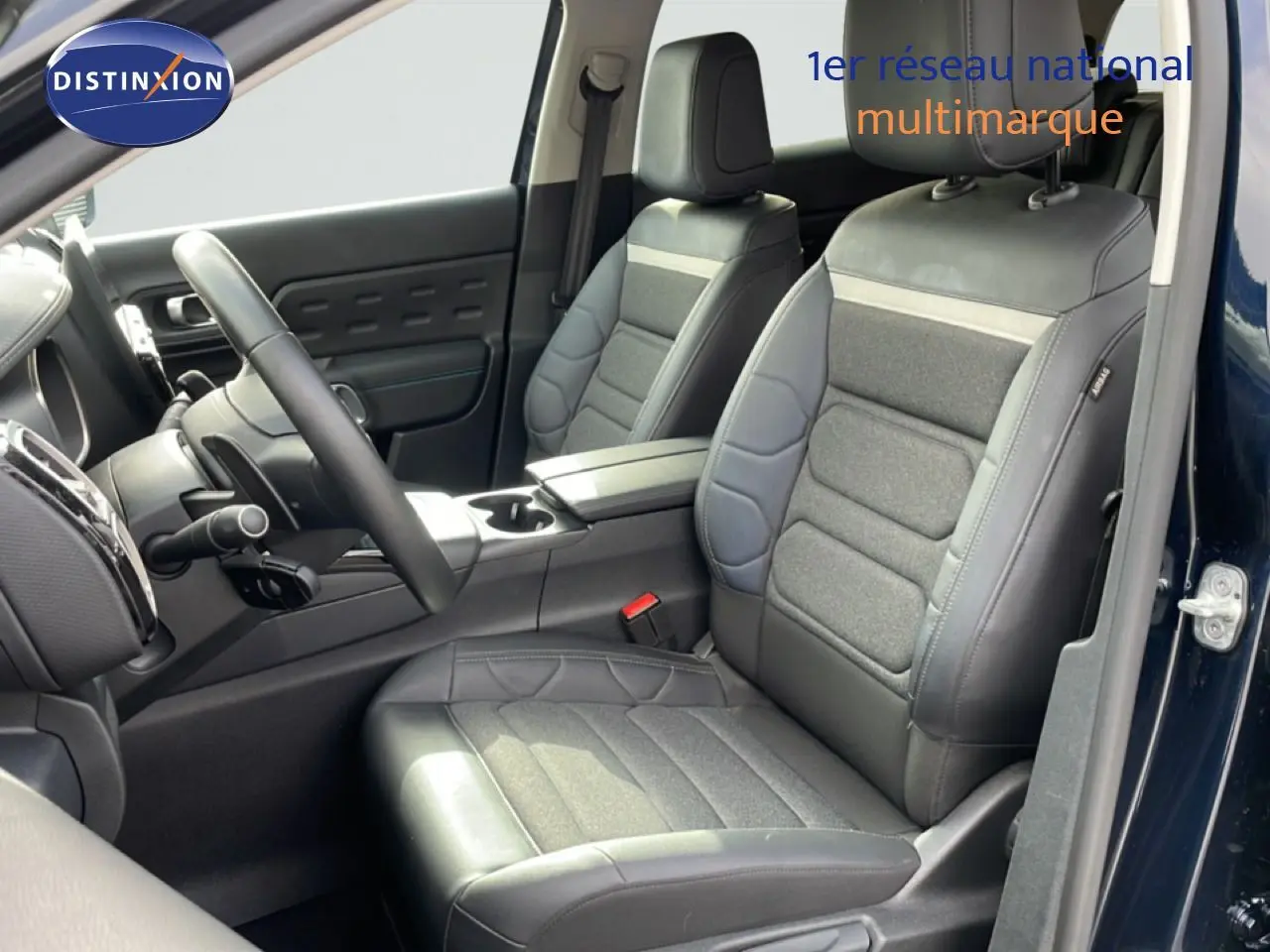 Vue intérieure côté conducteur du Citroën C5 Aircross 2024, sièges en tissu et cuir noir, porte ouverte côté droit.