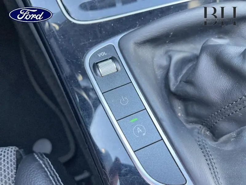 Gros plan sur la console centrale avec levier de vitesse cuir et commandes de volume et arrêt moteur d’une Mercedes Classe C argent iridium.