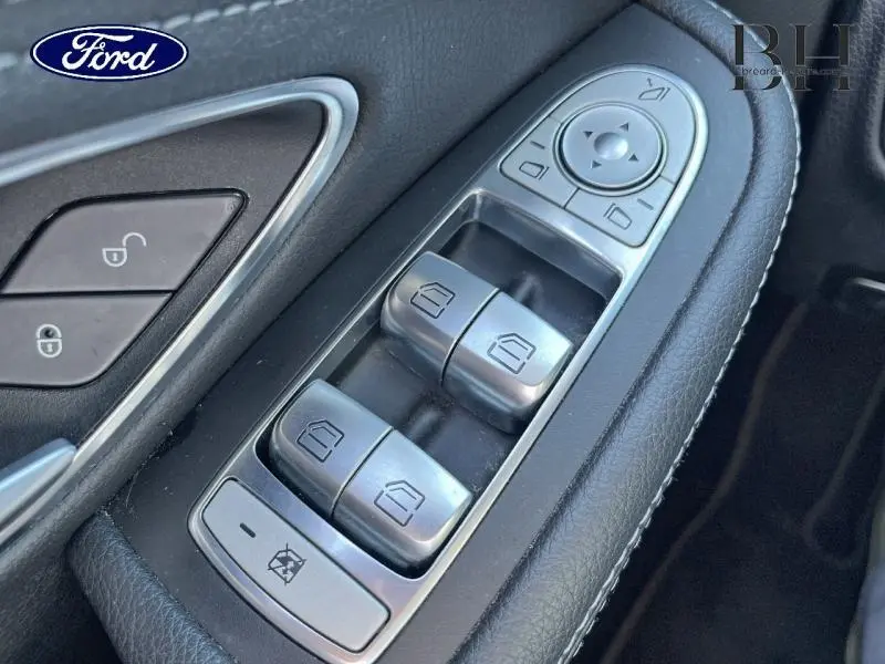 Gros plan sur les commandes de lève-vitres et rétroviseurs en plastique noir et argent dans une Mercedes Classe C 200 d Business.