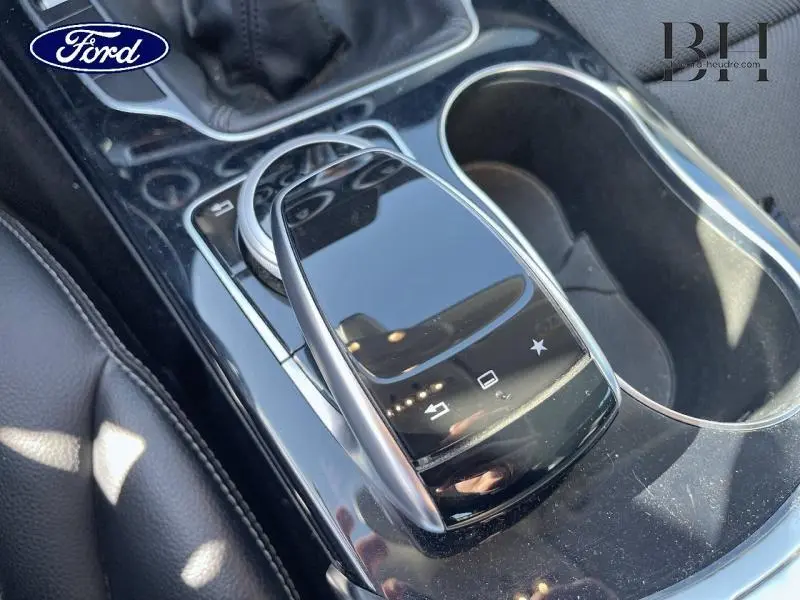 Gros plan sur la console centrale noire brillante avec pavé tactile et levier de vitesse cuir, intérieur cuir noir.