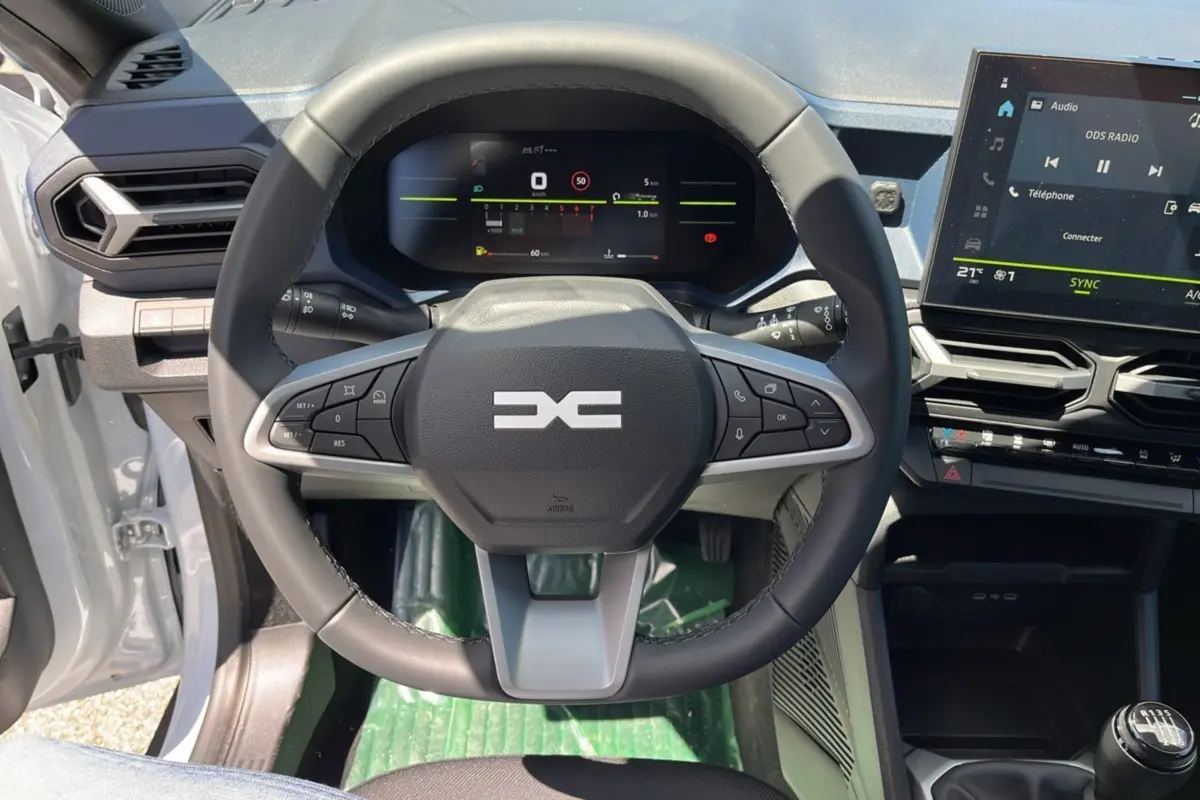 Vue intérieure centrée sur le volant cuir et le tableau de bord digital du Dacia Bigster blanc glacier 2025.