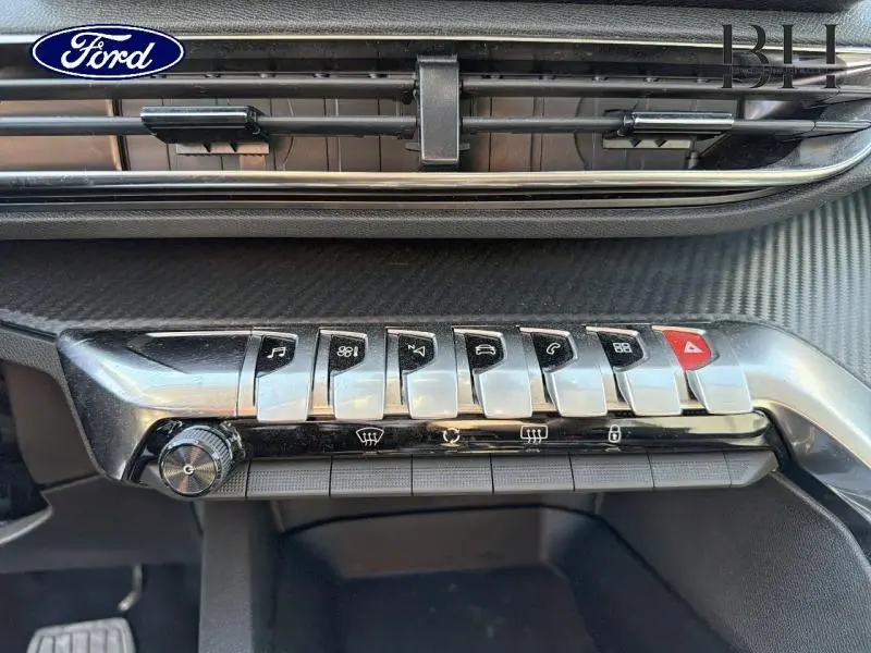 Gros plan sur la rangée de boutons chromés du tableau de bord du Peugeot 5008 gris Platinium, avec finition carbone.