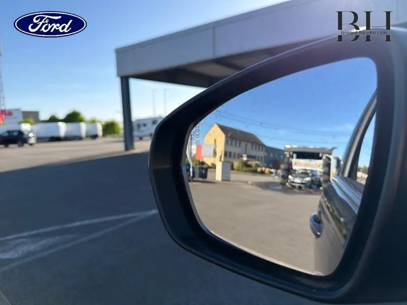 Rétroviseur extérieur droit d’un Peugeot 5008 gris Platinium, avec reflet d’un camion et bâtiment en arrière-plan.