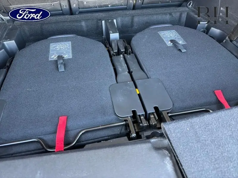 Vue rapprochée des sièges rabattus à plat arrière du Peugeot 5008 gris Platinium, montrant les sangles rouges de déverrouillage.