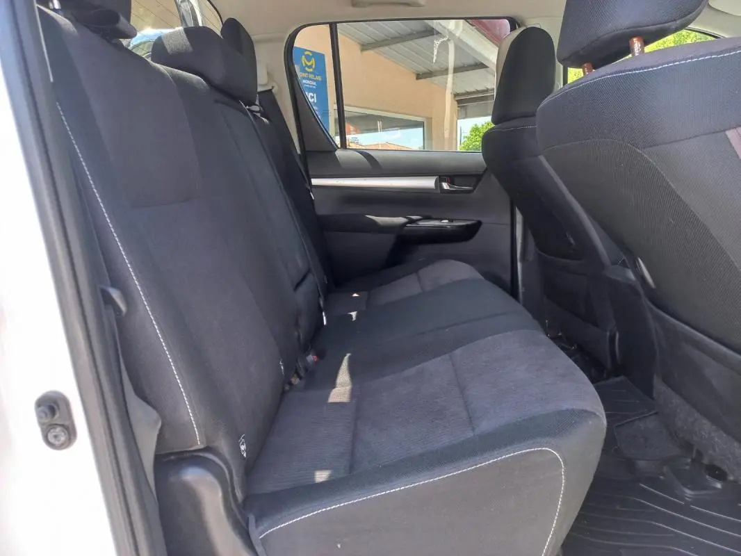 Vue intérieure côté gauche des sièges arrière en tissu noir du Toyota Hilux blanc double cabine de 2018.